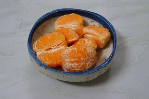 Free Close-up of peeled tangerines in a speckled ceramic bowl placed on a marble surface. Stock Photo