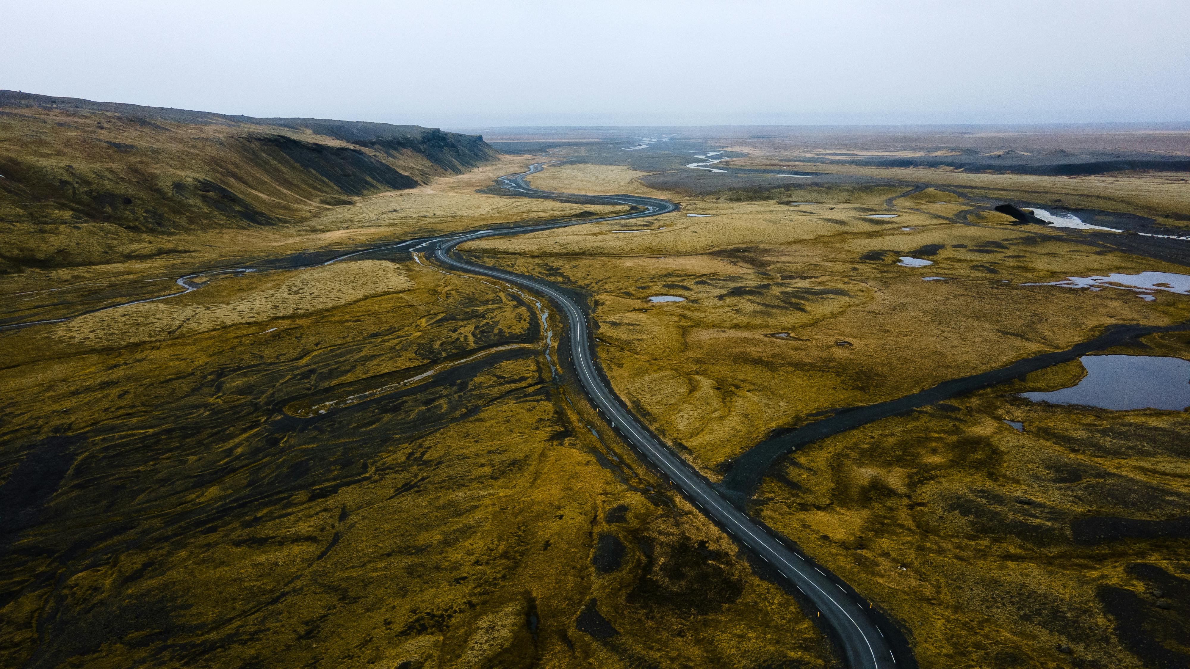 A breathtaking view of a winding road through the vast, scenic Icelandic landscape on a cloudy day.