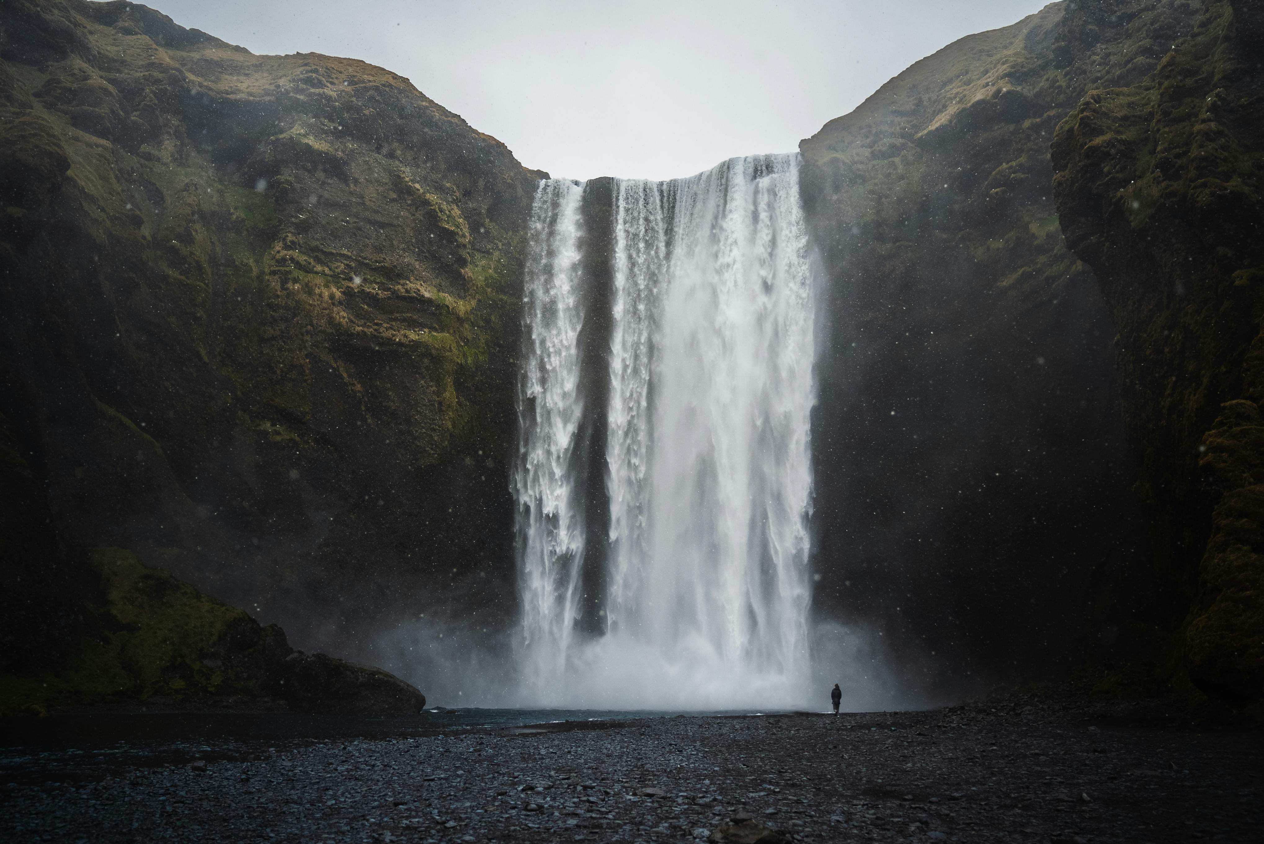 A close-up view of Skogafoss waterfall in Iceland with a person standing for scale.