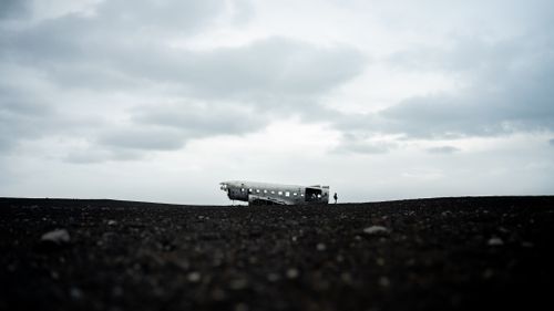 Free A haunting image of a plane wreck on a barren landscape under a cloudy sky, with vast emptiness. Stock Photo