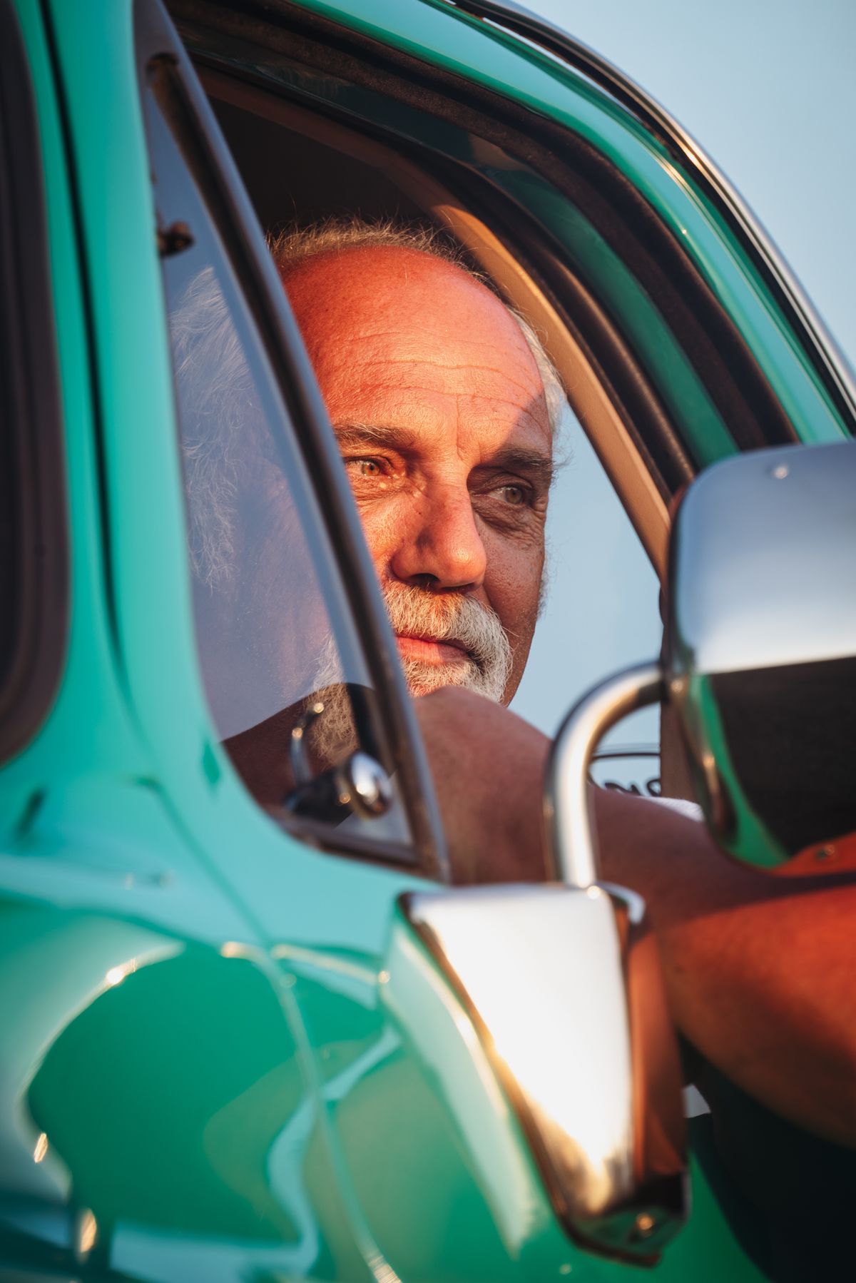 An older man driving a car, turning to look