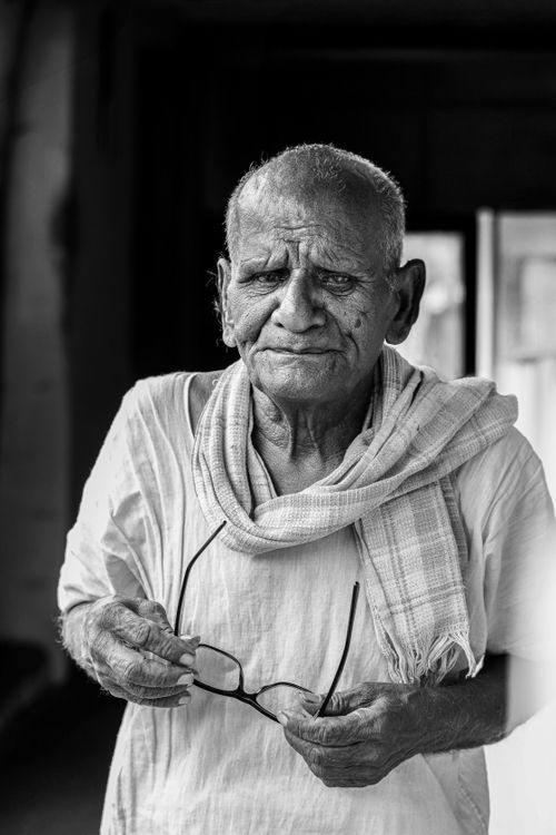 Free Portrait of a senior Indian man holding eyeglasses, wearing traditional attire in Coimbatore, Tamil Nadu. Stock Photo