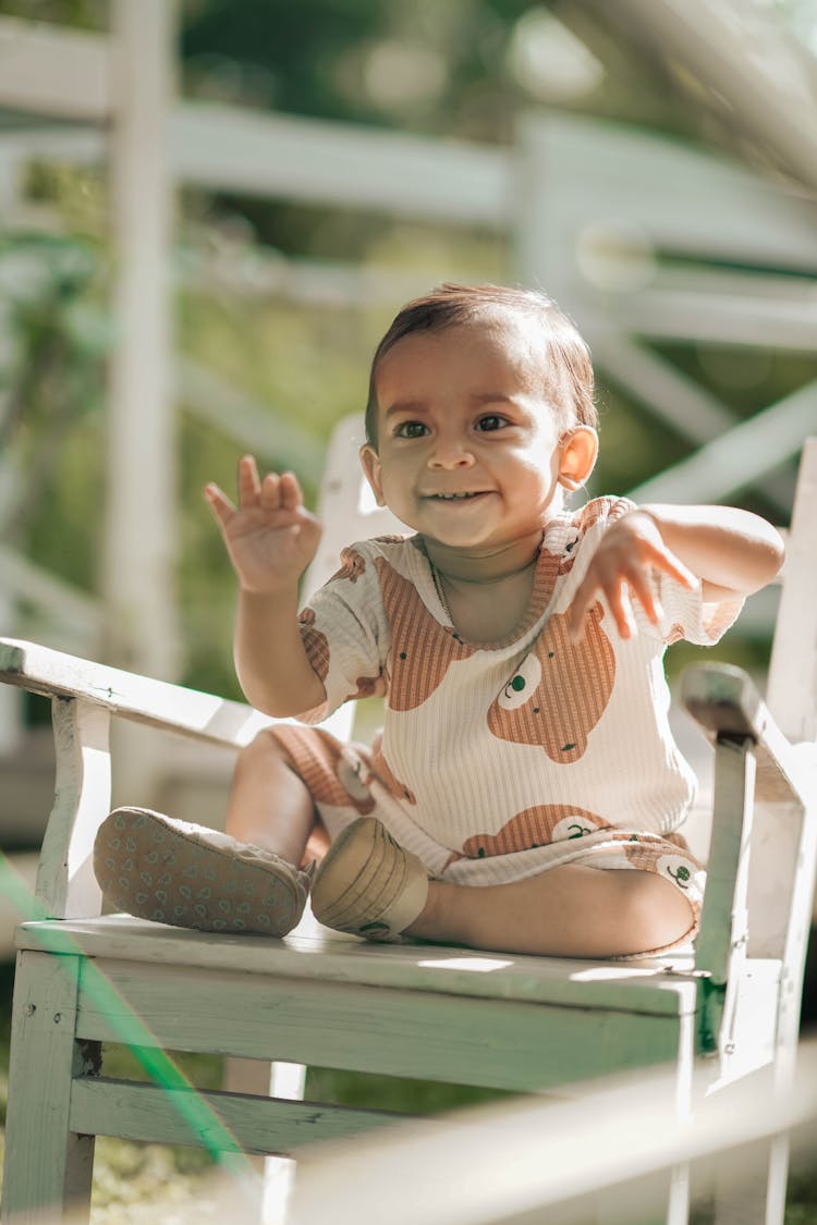 Portrait Of A Cute Toddler Sitting On A Wooden Chair