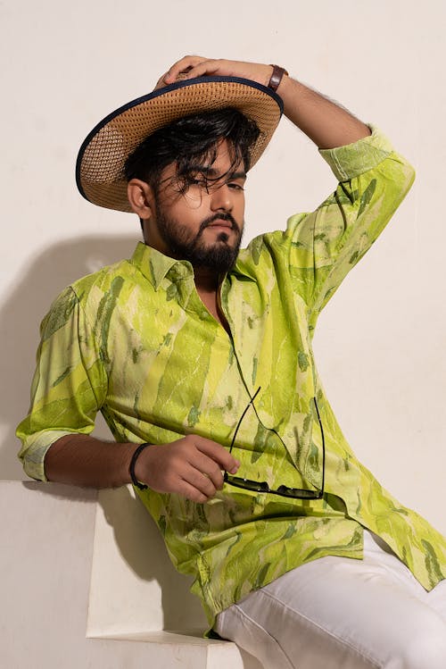 Man in Green Shirt Holds Hand on Sunhat