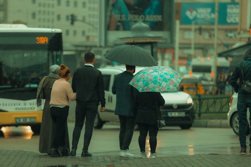 People with Umbrellas Standing on Sidewalk on Rainy Day