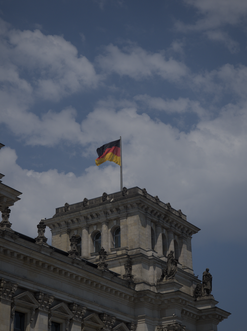 Free View of the Reichstag building in Berlin, showcasing its neoclassical architecture with the German flag waving on top. Stock Photo