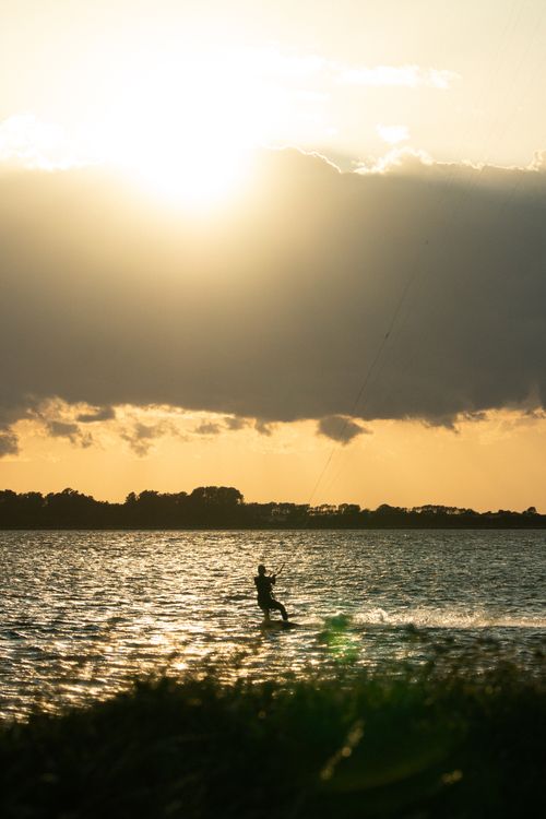 Free Kite surfer enjoying a thrilling sunset session on the calm waters of Wiek, Germany. Stock Photo