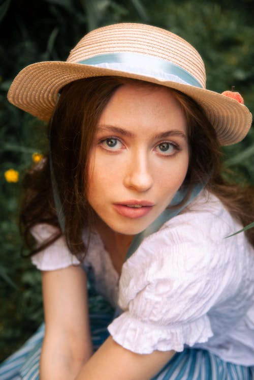 Young Brunette Woman Posing in a Straw Hat and White Blouse