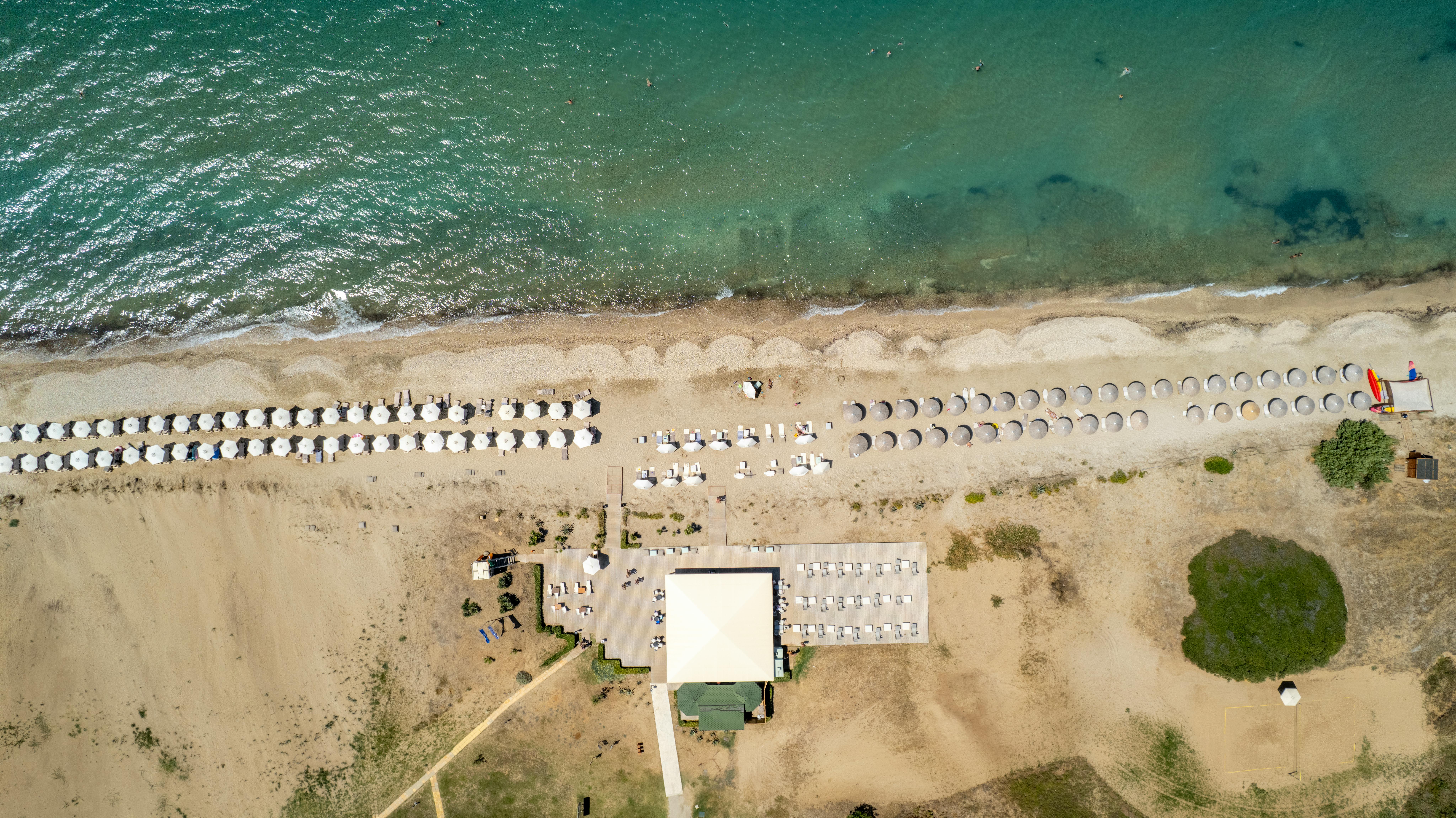 Stunning aerial view of a sandy beach with rows of umbrellas in Corfu, Greece.