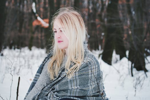 白雪皑皑的冬季森林里，一名围着格子围巾的金发女子，神情平静而沉思