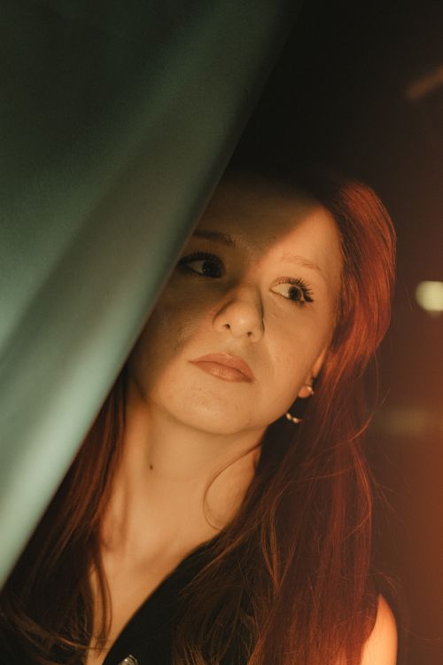 Free A thoughtful woman with long hair captured in a warm, moody light. Stock Photo
