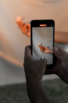 Person using smartphone to photograph artistic hand pose.