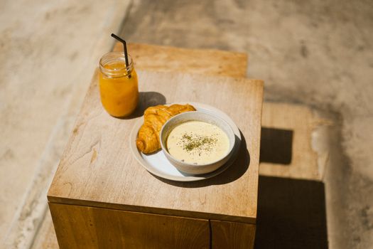 Bowl of Soup with Croissant and a Jar of Juice Standing on a Table