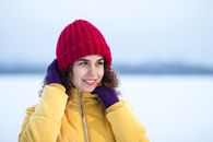 Young woman enjoying a winter day, wearing a bright red hat and yellow jacket.