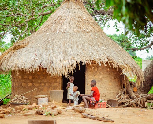 Kids Outside of a Traditional African Hut with a Thatched Roof in the Village 