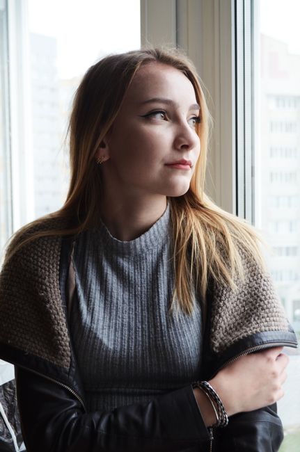 A serene portrait of a young woman gazing out a window, reflecting on life.