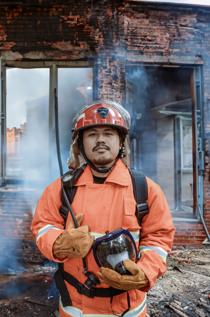 A determined firefighter standing in front of a burnt building in Semarang, Indonesia.