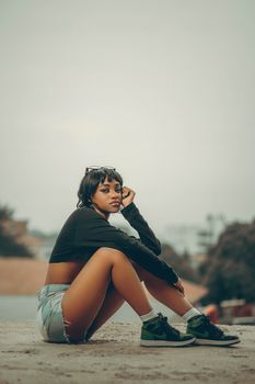 A trendy young woman sits on a rooftop, exuding confidence and style.