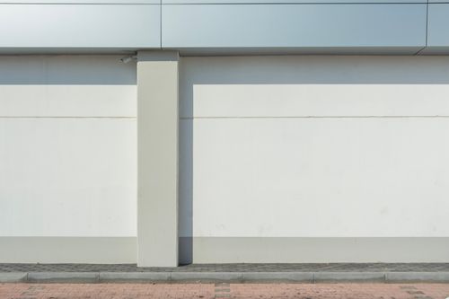 Free Sleek minimalist building facade featuring a seamless wall with urban sidewalk. Stock Photo