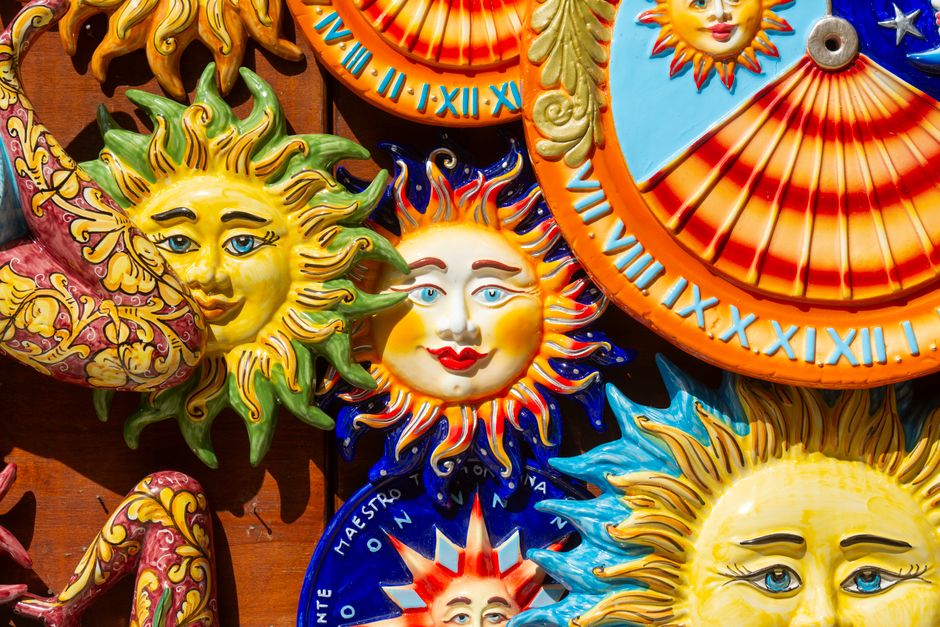 Colorful ceramic sun faces with intricate designs, capturing vibrant decor in sunlight.