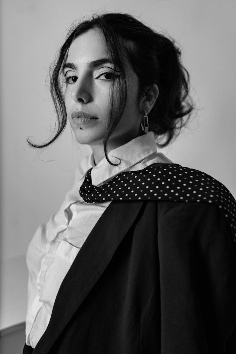 Black And White Photo Of A Brunette Woman Posing In Blazer And Tie