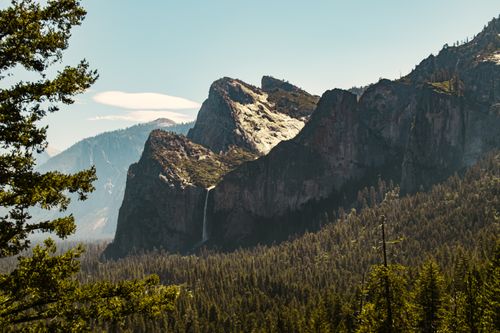 Free Breathtaking view of Yosemite Valley's rocky landscape featuring lush forests and a waterfall. Stock Photo