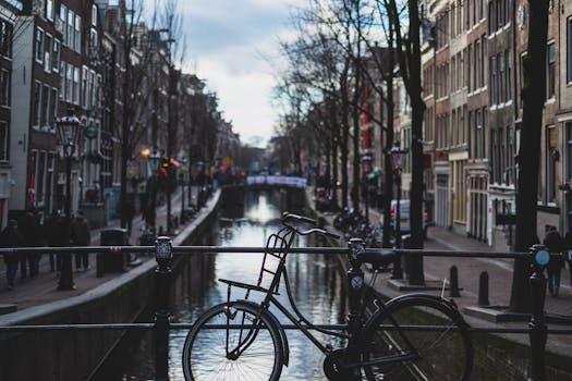 A classic bike on a bridge over an Amsterdam canal, capturing the city's charm. by _ Harvey