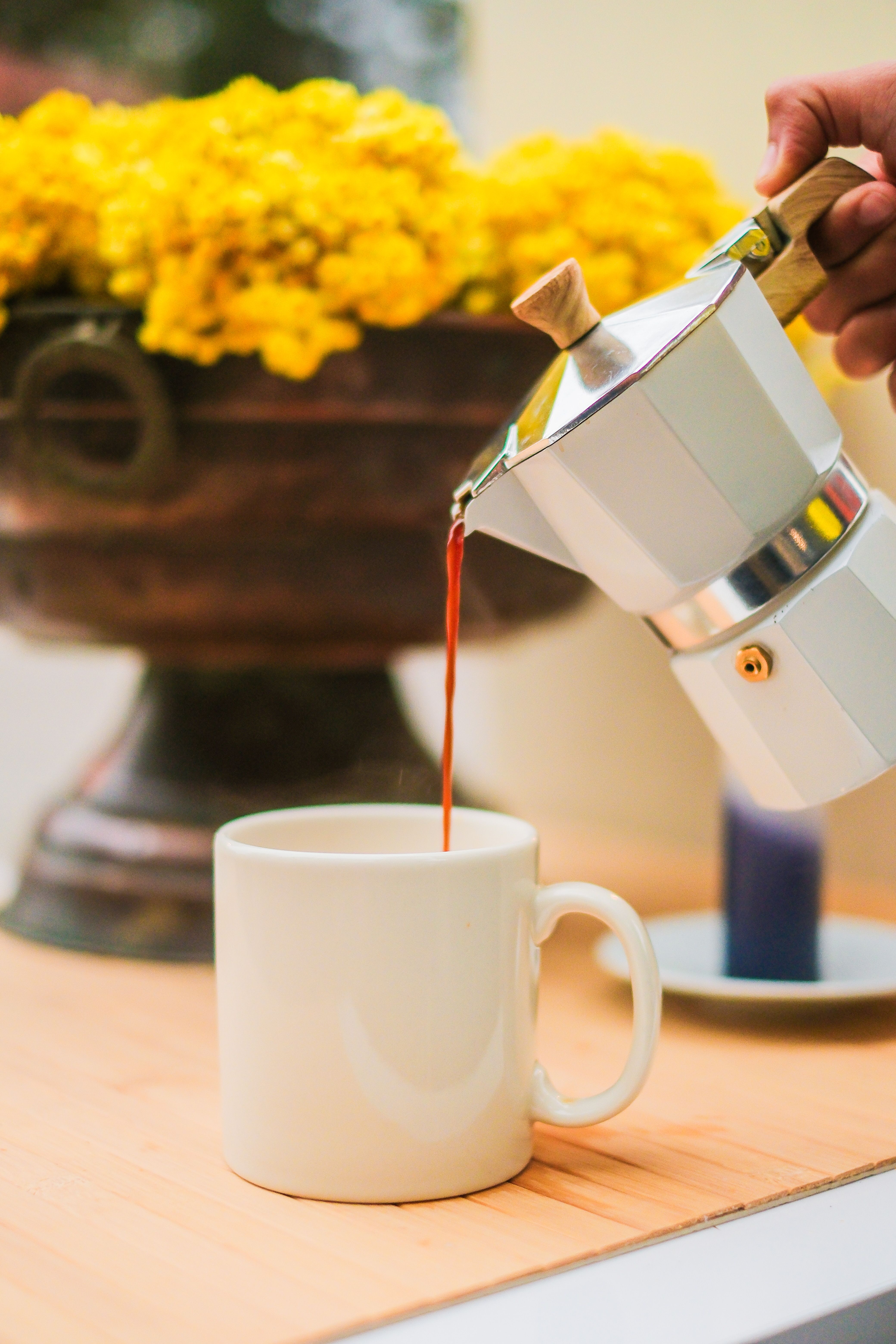 Close-up of a moka pot pouring fresh coffee into a mug on a table.