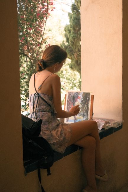 A woman painting in a sunny Sevilla courtyard, capturing artistic inspiration outdoors.