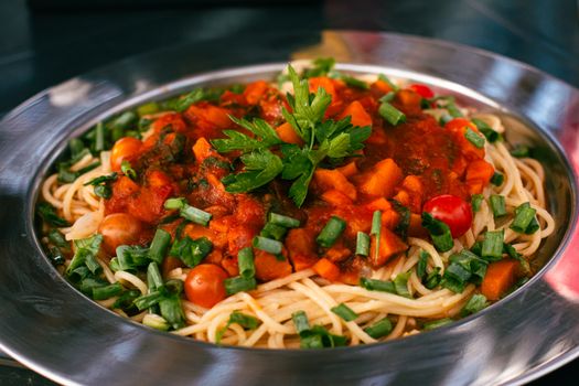 Close-up of a vibrant vegetable spaghetti dish with fresh tomato sauce and herbs.