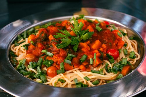 Free Close-up of a vibrant vegetable spaghetti dish with fresh tomato sauce and herbs. Stock Photo