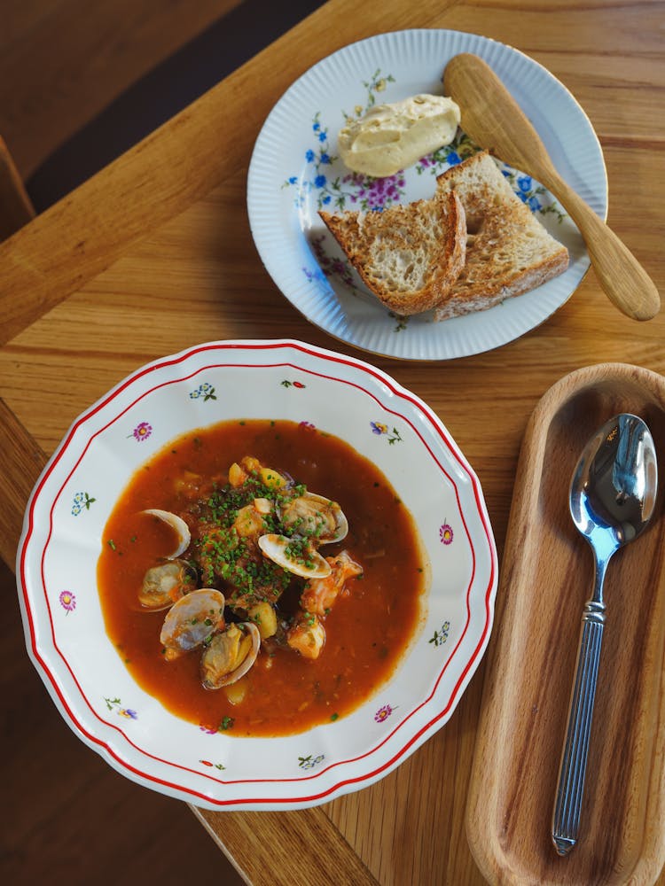 Plate Of Soup With Toasted Bread And Butter On A Table