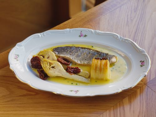 Free A gourmet plate featuring fresh fish, artichokes, and sun-dried tomatoes beautifully presented. Stock Photo