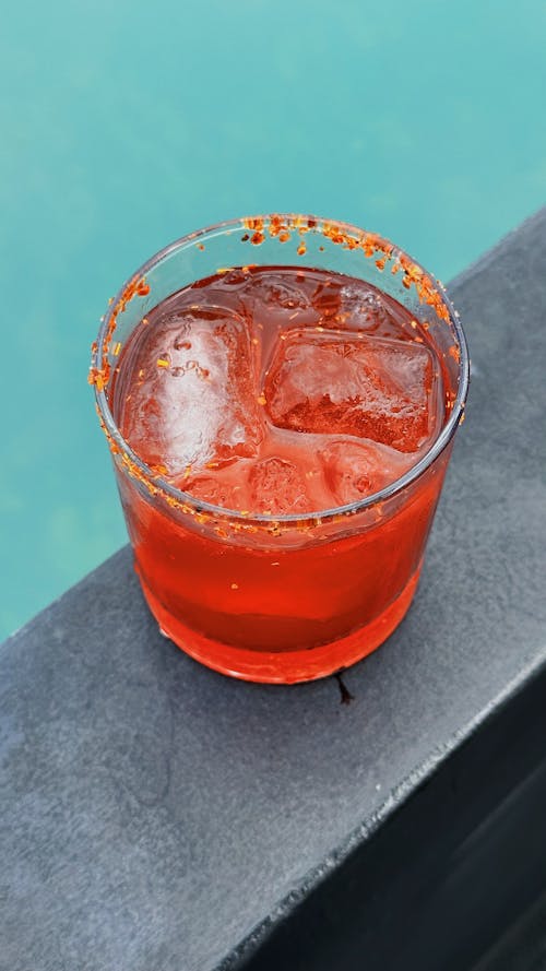 Glass of Red Cocktail with Ice Cubes and Spiced Rim