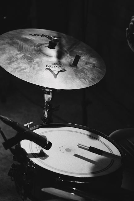 Close-up of a black and white drum set with cymbals captured in a dimly lit setting.