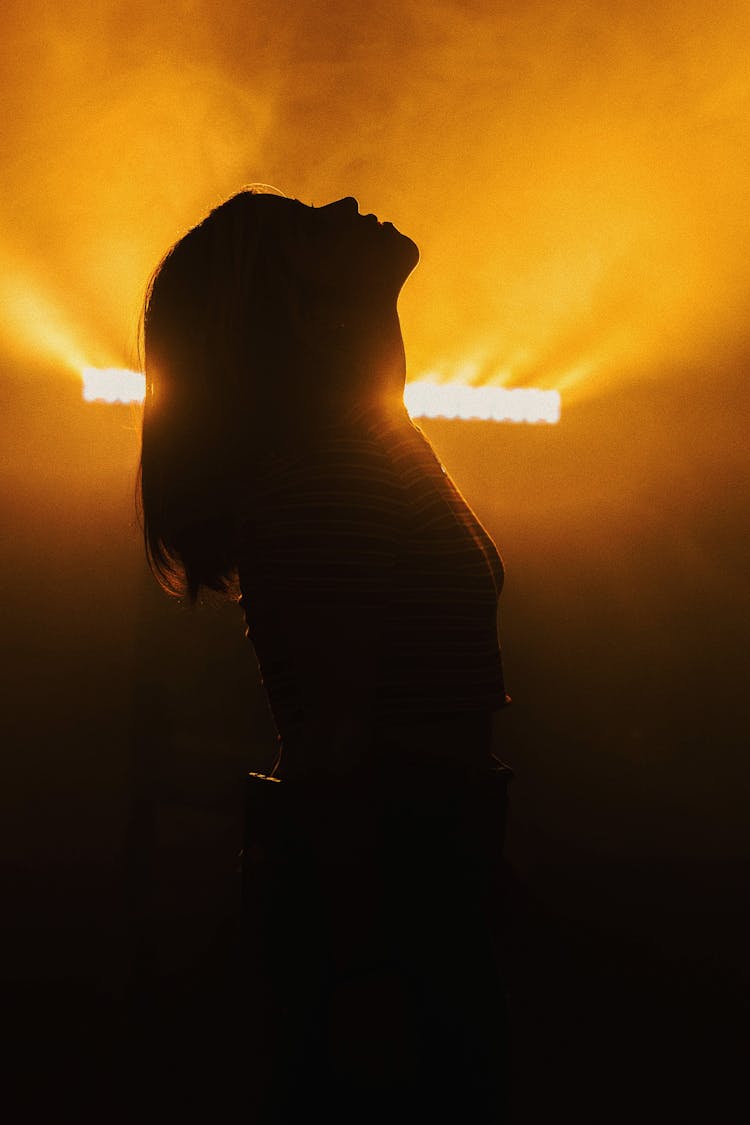 Silhouette Of A Woman Standing With Head Back On The Background Of Bright Light 