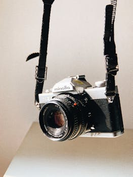 A classic Minolta 35mm SLR camera hanging by its strap, exuding vintage charm.
