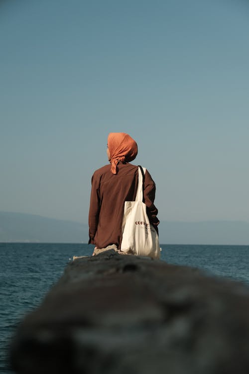 Woman in Hijab and with Bag on Sea Shore
