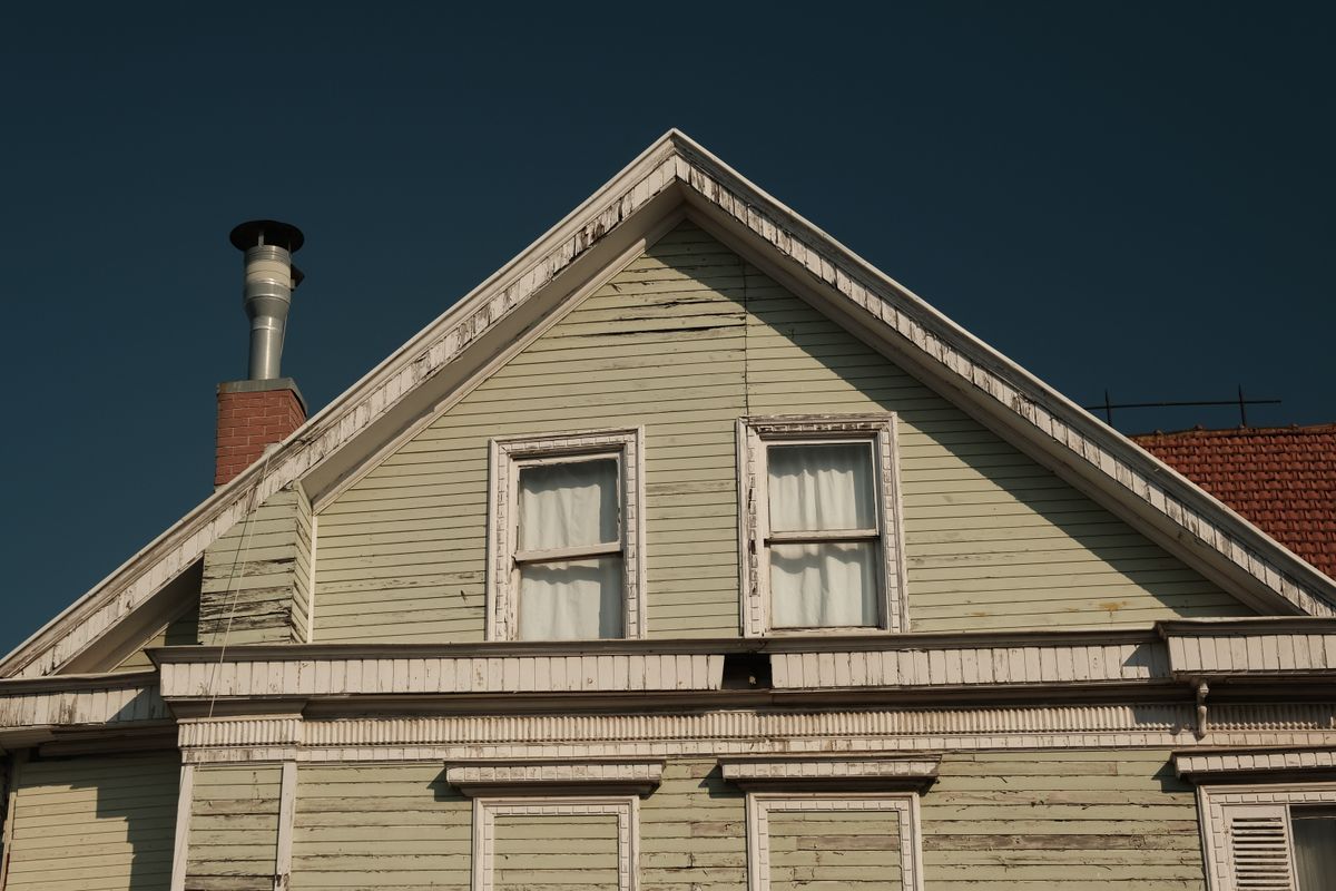 An old wooden house with a brick chimney against a clear sky