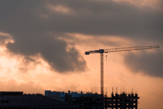 Silhouette of a construction crane against a vibrant sunset in Lima, Perú.