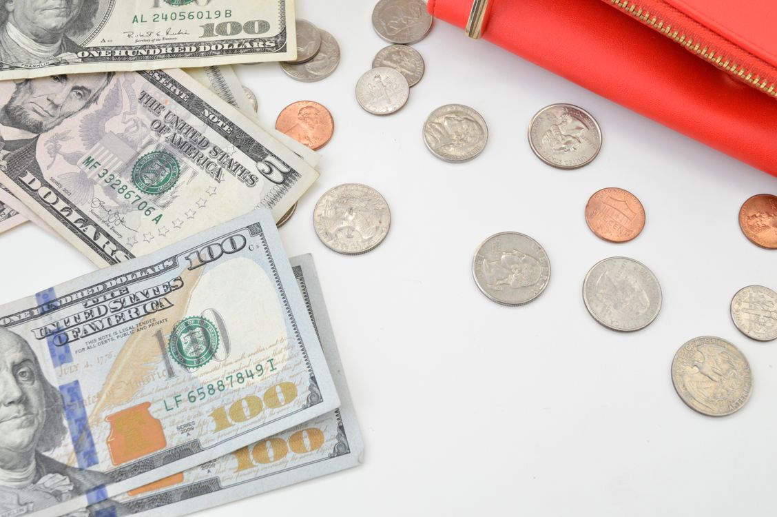 Free Detailed image of US dollars and coins spread with a red wallet on a white surface, ideal for financial concepts. Stock Photo