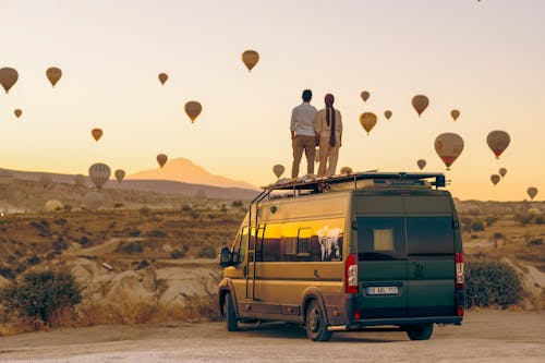 Couple Watching Rising Hot Air Balloons from the Roof of an RV Van