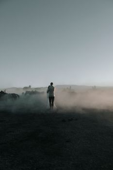 A couple embracing in a misty rural landscape with livestock at dawn, creating a moody atmosphere.
