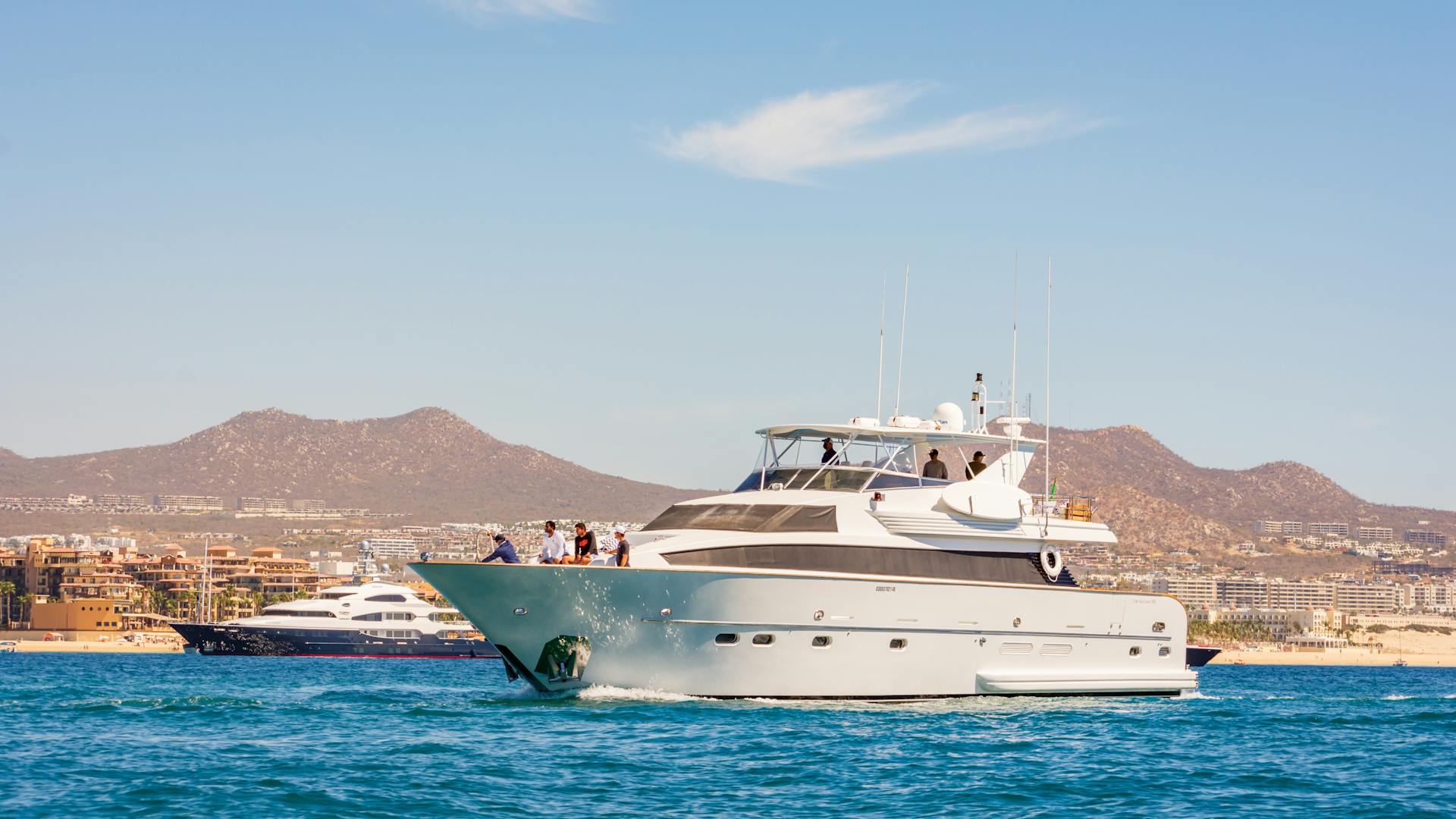 Elegant yacht sailing in Cabo San Lucas with scenic views of mountains and harbor.