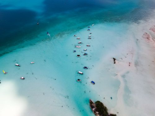 Free Drone shot of tourist boats floating in clear turquoise waters, ideal for travel and tourism themes. Stock Photo