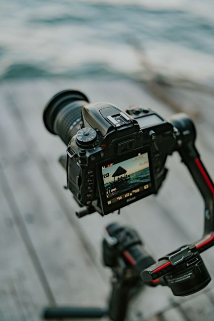 A DSLR camera mounted on a tripod capturing a scenic waterfront view, emphasizing photography setup.