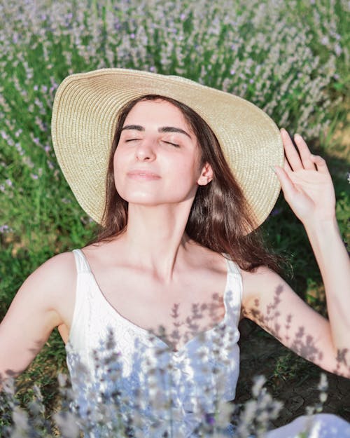 Woman in Hat and with Eyes Closed on Meadow