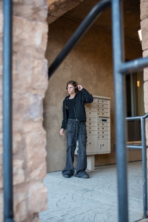 Free Man wearing headphones and casual attire stands near mailboxes in urban setting. Stock Photo