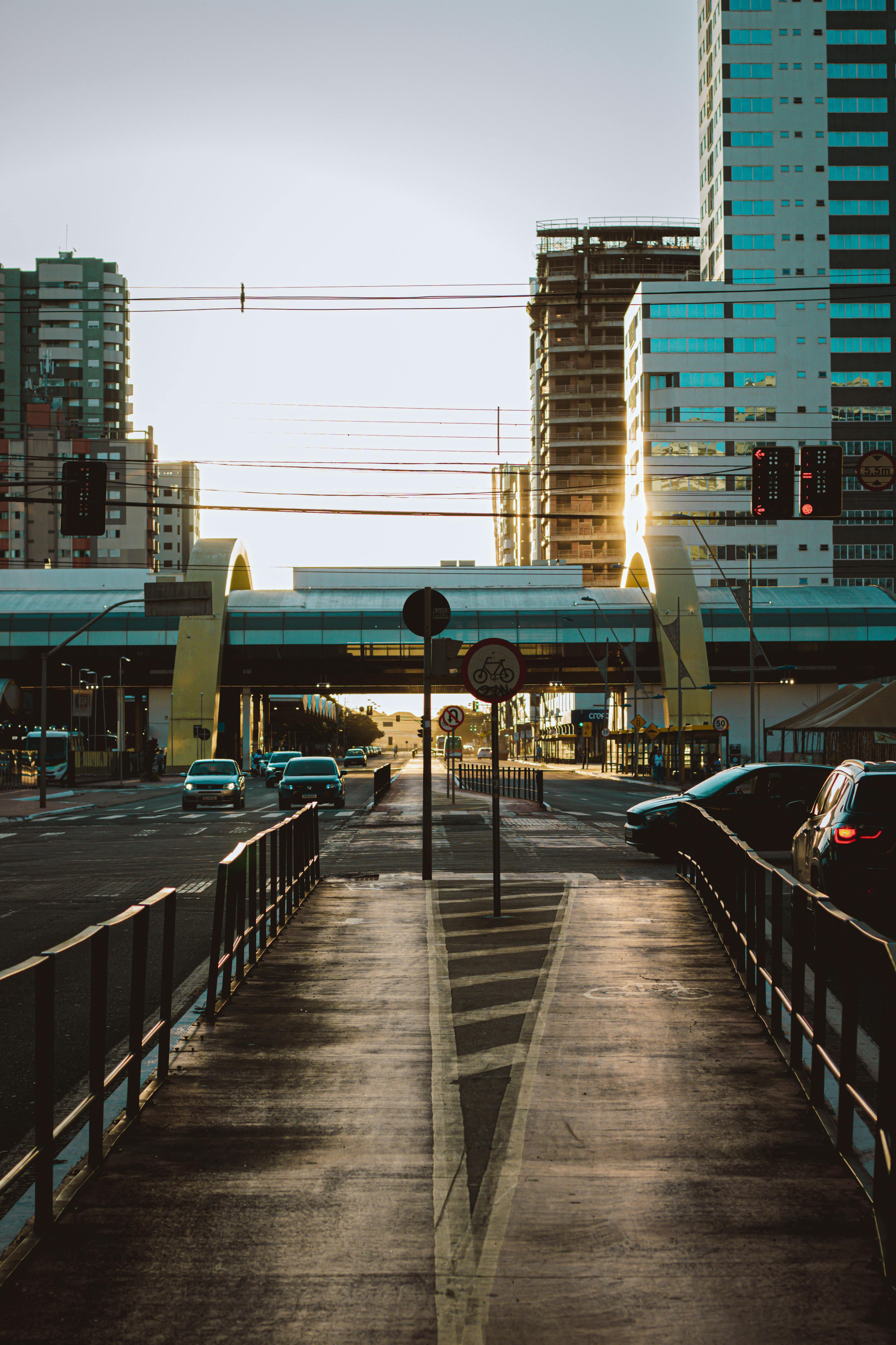 Sunrise over an urban street with modern architecture in Maringá, Brazil, featuring a pedestrian path and cityscape.