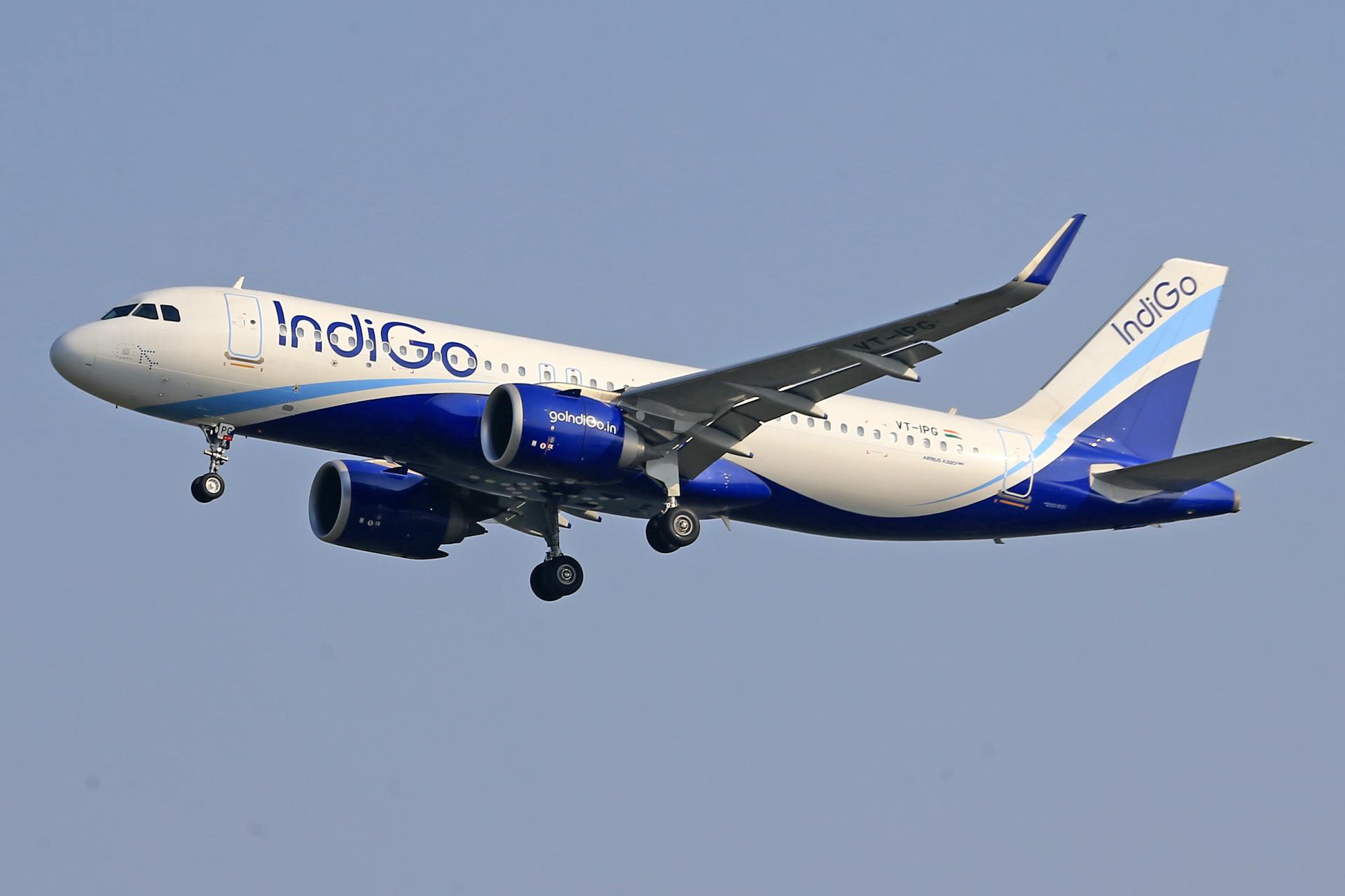 IndiGo commercial airline flying against a clear blue sky, signifying travel and aviation.